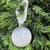Decorative white ornament with feather on a green tree